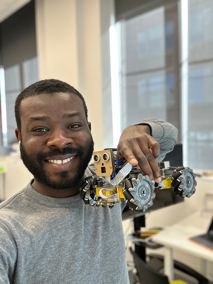 Prosper Habada smiling and holding a robot